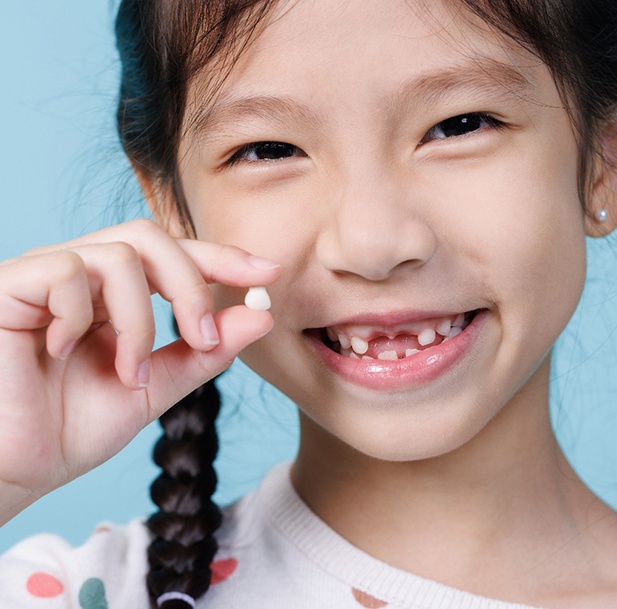 Little girl with braids holding extracted tooth