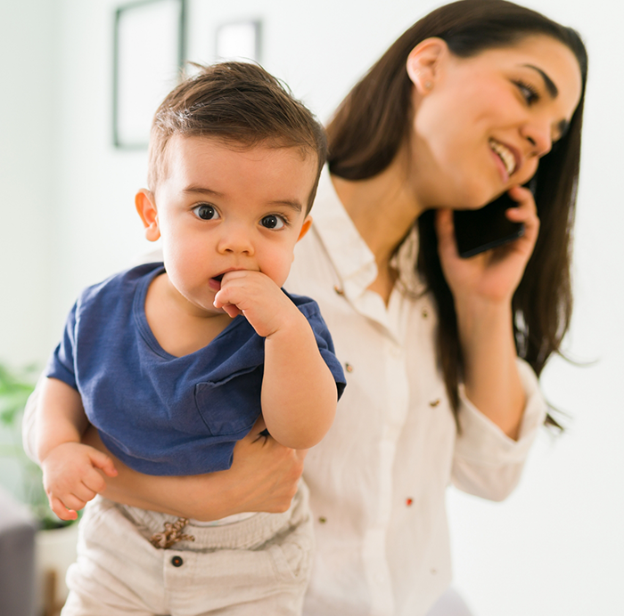 Young boy sucking his thumb while his mother holds him