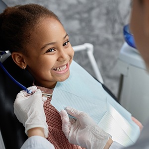 Dentist placing bib on smiling child