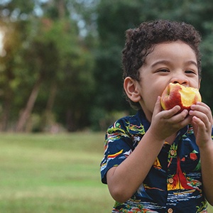 Child eating apple at park