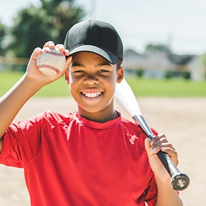 Child with baseball and bat smiling