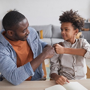 Father and son fist-bumping in living room