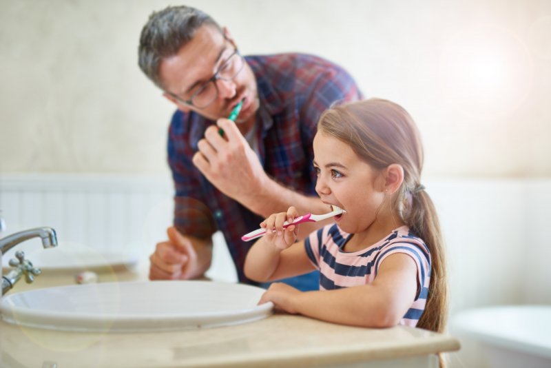 dad and daughter brushing their teeth