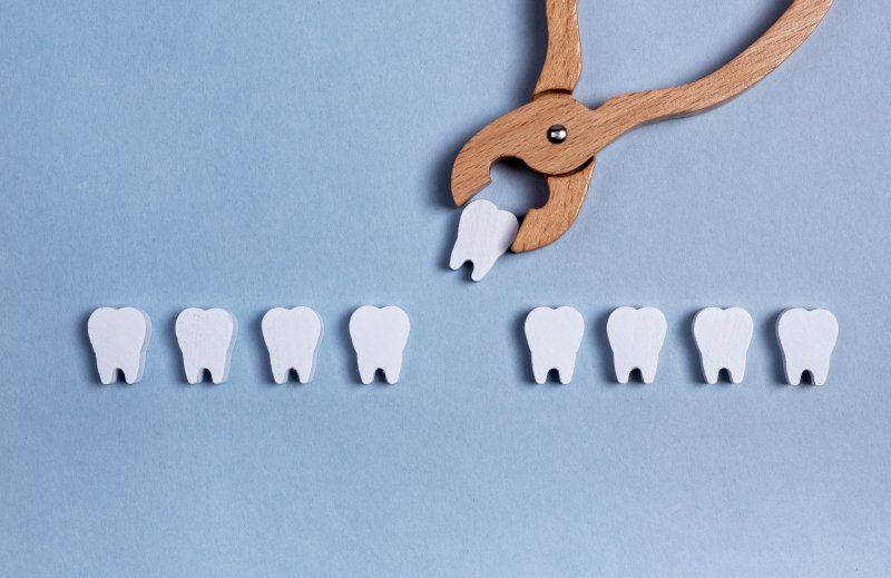 Wooden toy dental instrument removing toy tooth.